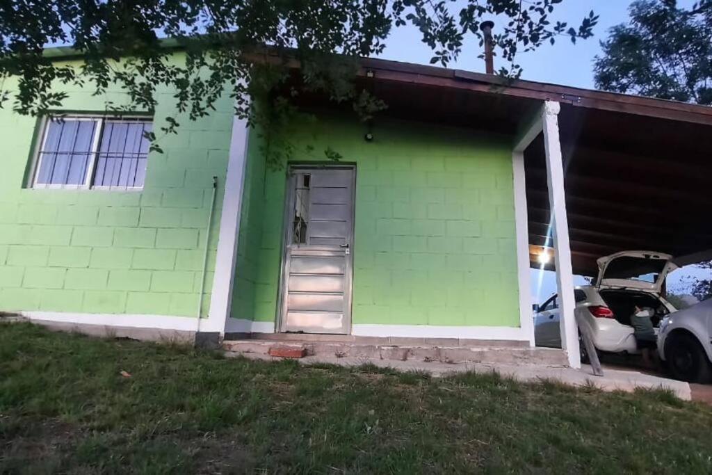 une maison verte avec une voiture garée devant elle dans l'établissement Casa V.Giardino pileta y cochera, à Villa Giardino