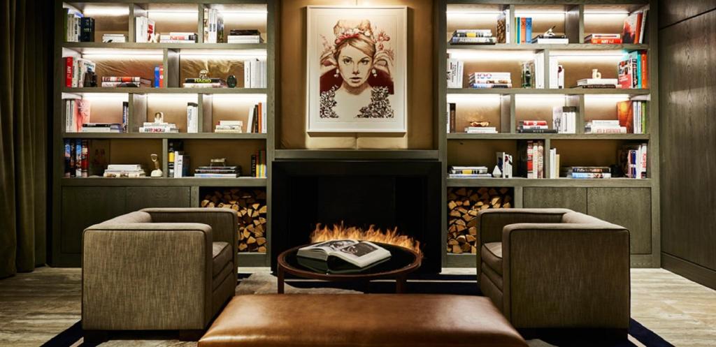 a library with two chairs and a fireplace at SIXTY SoHo in New York