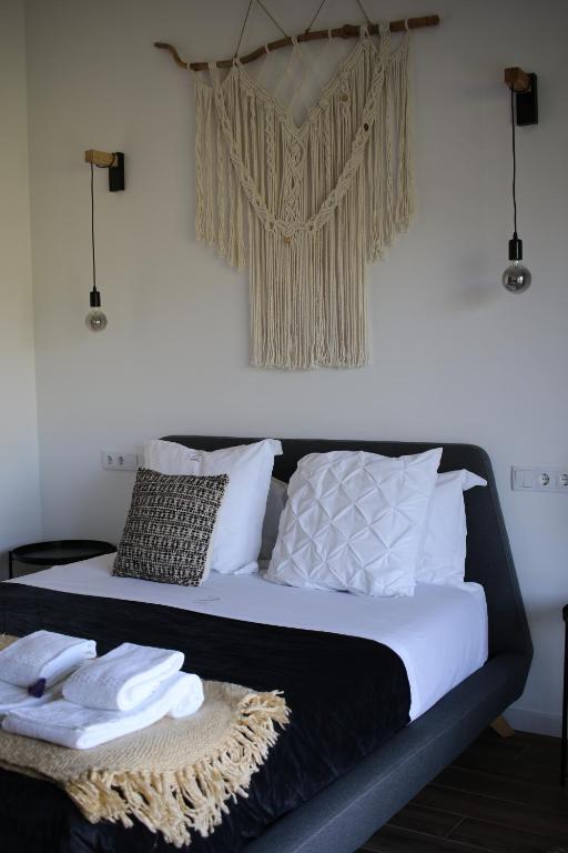 a bed with white sheets and pillows in a room at Zambujal Suites in Sesimbra