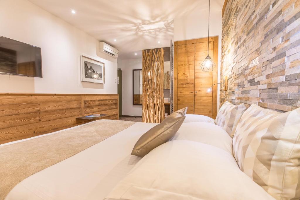 Un dormitorio con una gran cama blanca y una pared de ladrillo en Hôtel des Princes, Chambéry Centre, en Chambéry