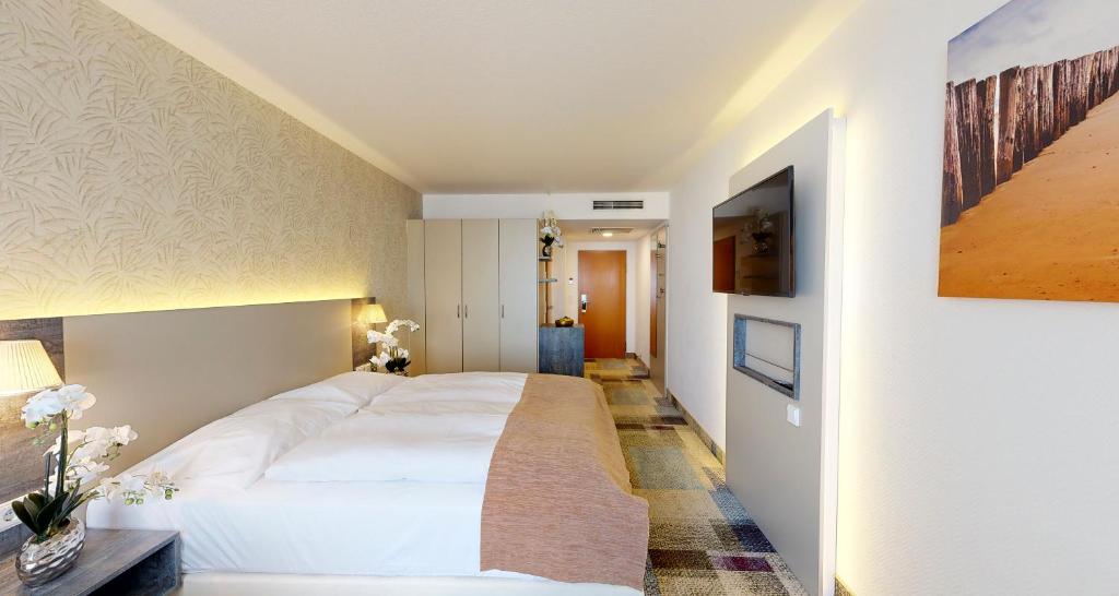 ein Schlafzimmer mit einem großen weißen Bett in einem Zimmer in der Unterkunft PLAZA INN Regensburg in Regensburg