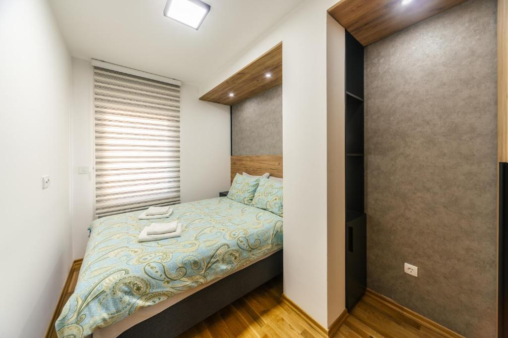 a small bedroom with a bed and a closet at Harizma apartmani - Iris in Kragujevac