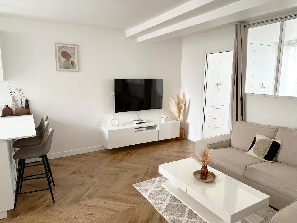 a white living room with a couch and a tv at Appartement central niché en centre-ville in Saint-Germain-en-Laye