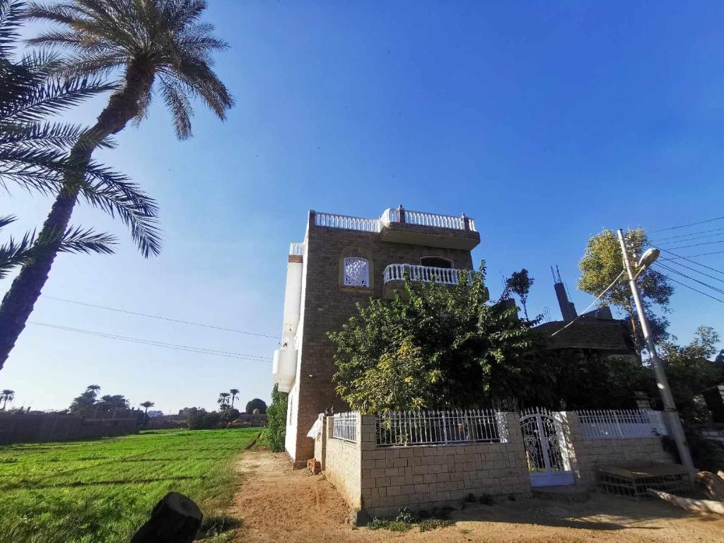 a building with a clock tower with a palm tree at Dream Garden Luxor in Luxor