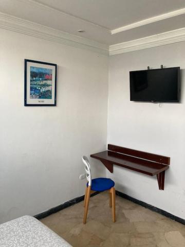 a bedroom with a desk and a television on a wall at Pablo´s House in Guayaquil