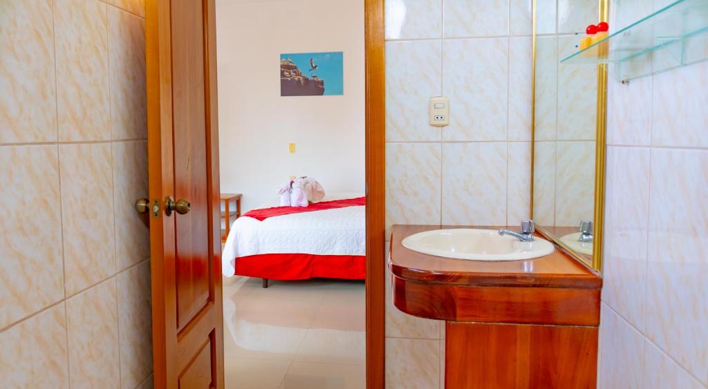 baño con lavabo y cama en Gran Hostal Tintorera en Puerto Villamil