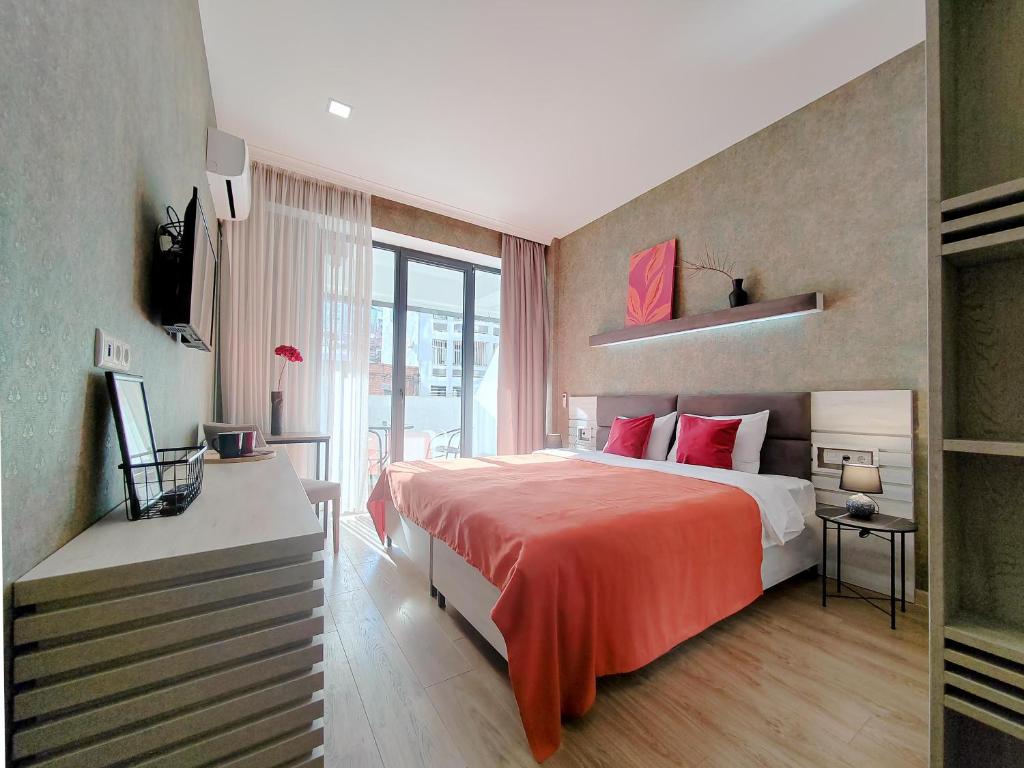 um quarto com uma cama grande e um cobertor vermelho em Round Garden Hotel em Tbilisi