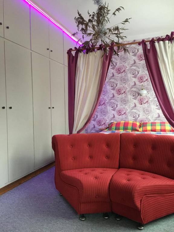 a red couch in a room with purple curtains at Monikas in Lapmežciems