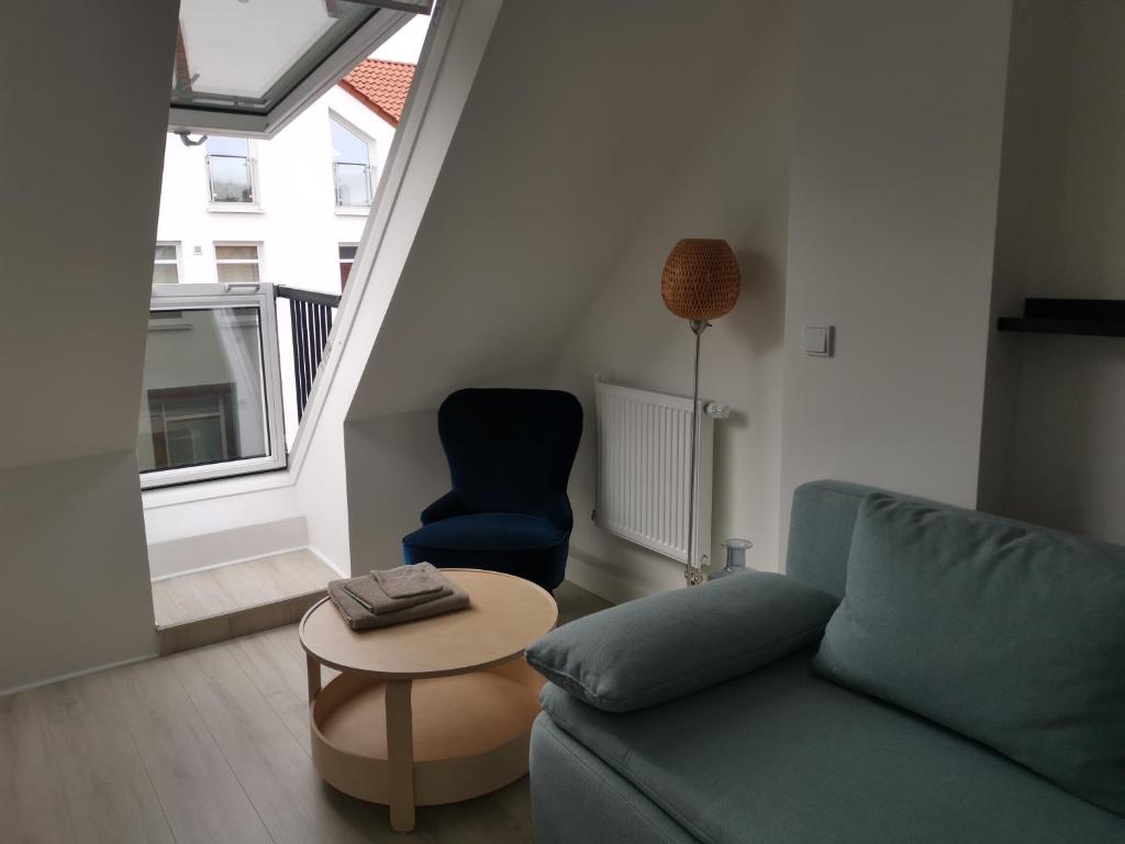 ein Wohnzimmer mit einem Sofa, einem Tisch und einem Stuhl in der Unterkunft Dachzimmer mit Kochecke und Duschbad, nahe Messe in Hannover