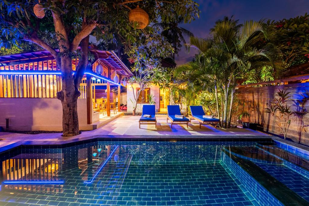 a swimming pool with blue chairs next to a house at Paradise Luxury Villa in Gili Air