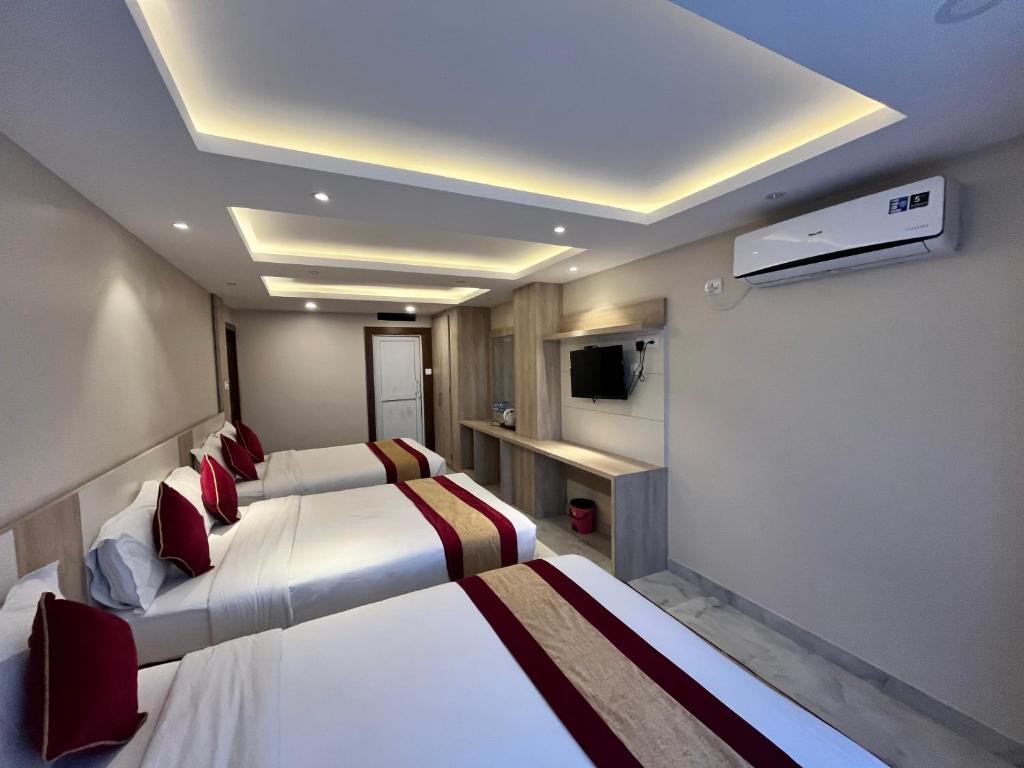 een hotelkamer met drie bedden en een televisie bij Hotel prime suite in Kathmandu