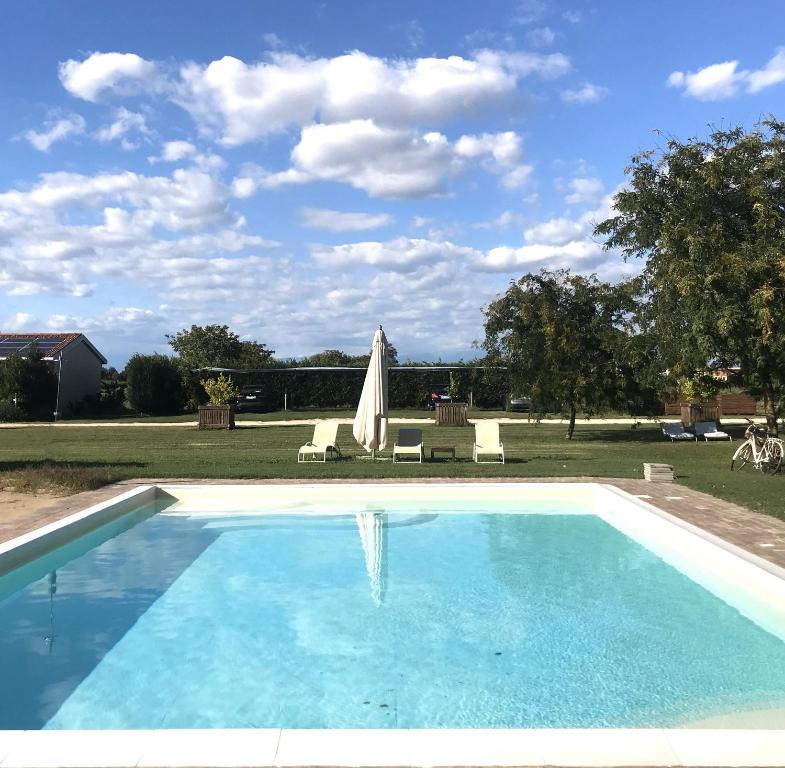 una piscina azul con sombrilla y sillas en La Foresteria di Borgogelsi Apartments, en Sanguinetto