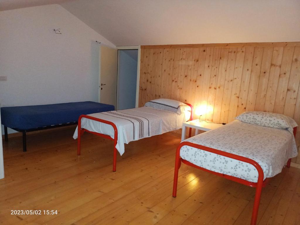 Habitación con 2 camas, paredes de madera y suelo de madera. en Appartamenti Regina Margherita, en Calasetta