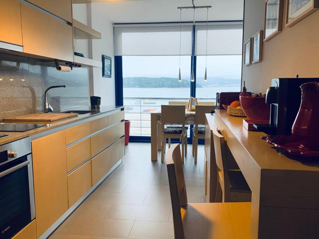 uma cozinha com uma grande janela e uma mesa com cadeiras em Apartamento exclusivo con vistas al mar em Outes