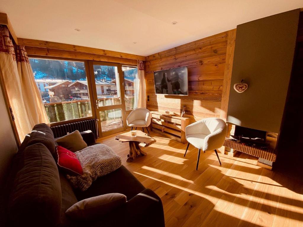 a living room with a couch and a large window at Appartement La Clusaz, 3 pièces, 6 personnes - FR-1-459-203 in La Clusaz