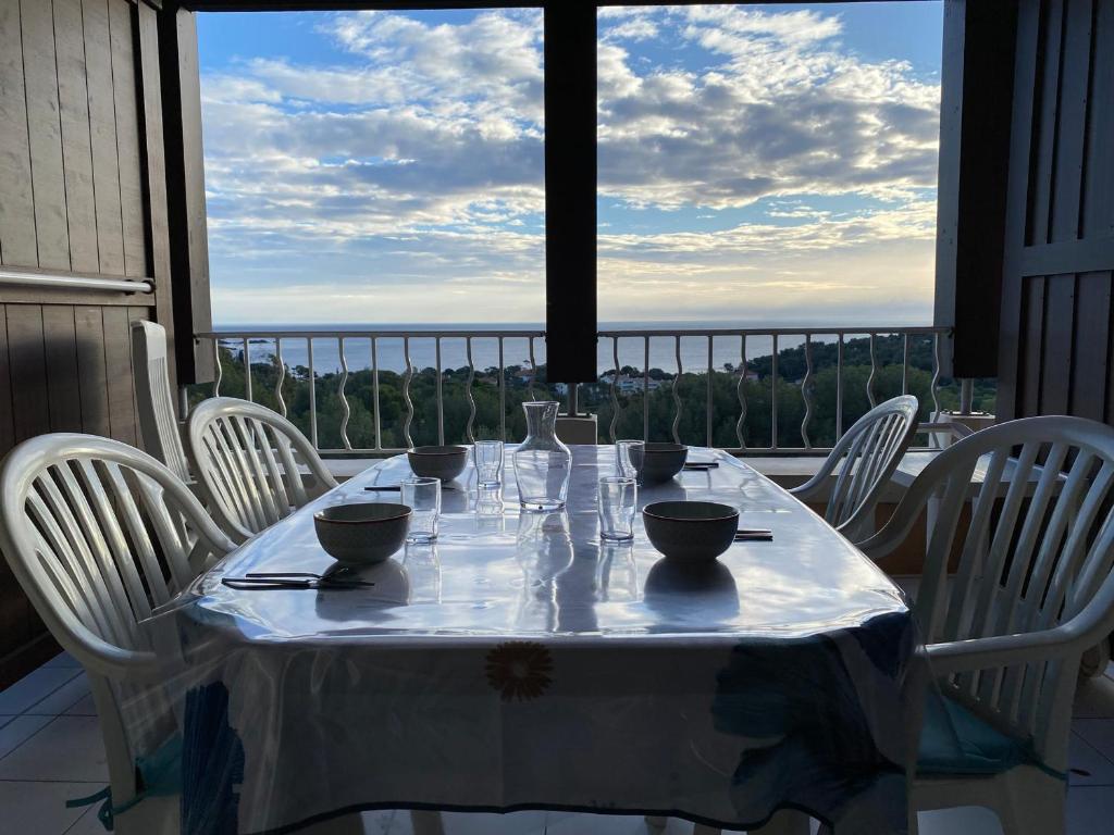 une table avec des chaises blanches et une table avec vue dans l'établissement Appartement 2 pièces avec terrasse et vue mer, accès piscine et parking inclus - FR-1-504-677, à Saint-Raphaël