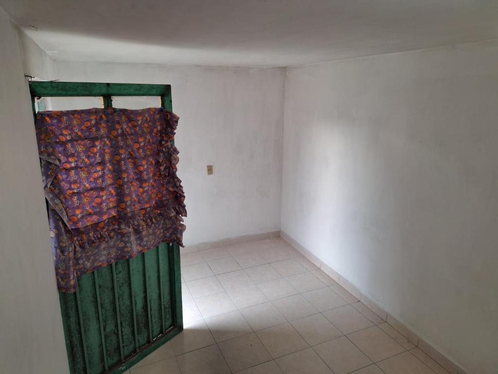 an empty room with a green door with a curtain at Cuartos a Pie de Carretera Mexico-Teotihuacan in Acolman de Netzahualcóyotl