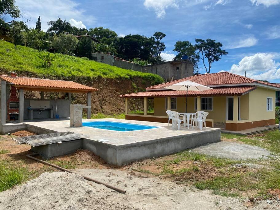 een huis met een zwembad en een parasol bij Excelente casa com piscina próximo SP in Nazaré Paulista