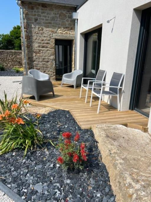 une terrasse en bois avec des chaises et des fleurs sur une maison dans l'établissement Maison en Baie du Mont St Michel, à Le Val-Saint-Père