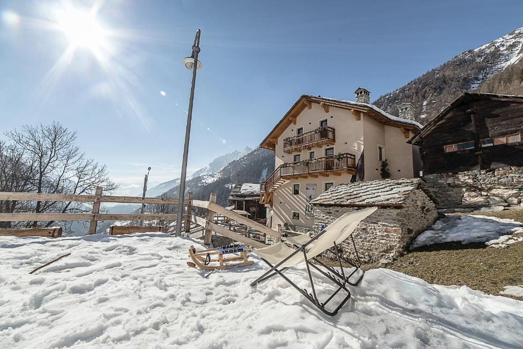 einen Stuhl im Schnee vor einem Gebäude in der Unterkunft Alpe Rebelle in Bionaz