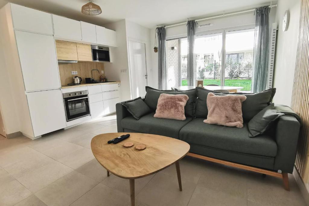 un salon avec un canapé vert et une table dans l'établissement Cocoon with terrace at 2 steps from the sea, à La Baule