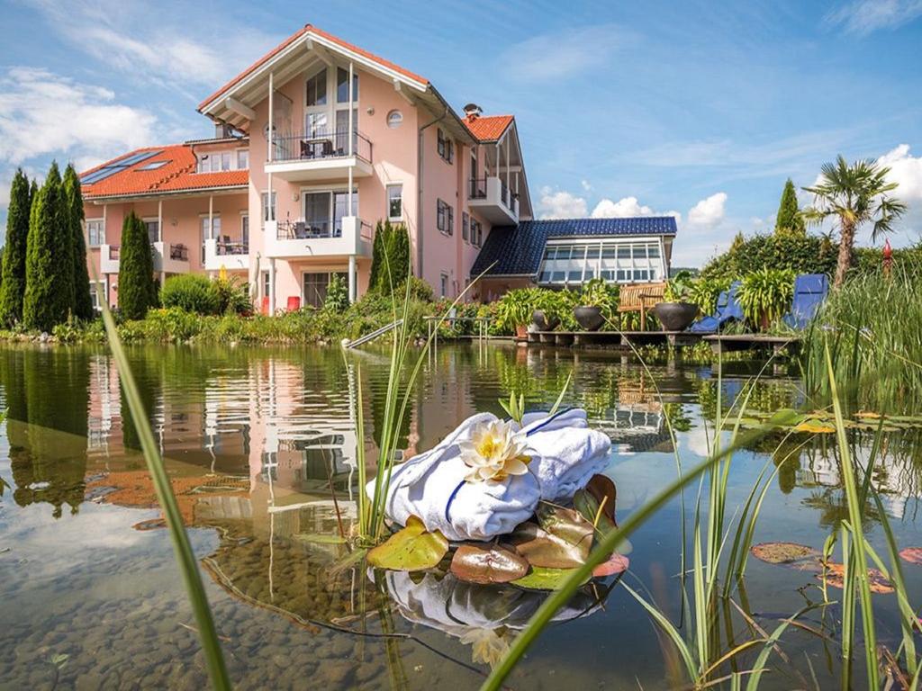 ein Haus auf einem Teich vor einem Haus in der Unterkunft Wellnesshof Blenk in Wertach