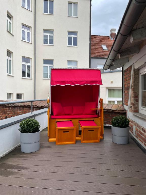 einen roten Stuhl auf einem Balkon mit zwei Pflanzen in der Unterkunft Gemütliches Häuschen in Schwerin