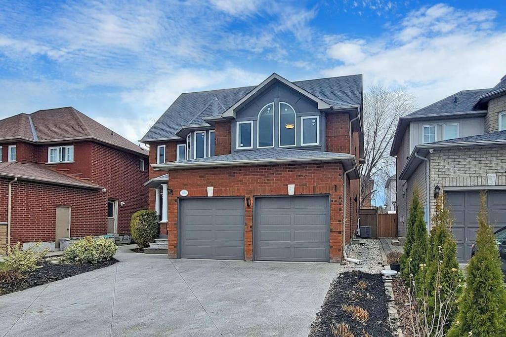 a brick house with two garage doors in a driveway at Superhouse with space for all! in Pickering