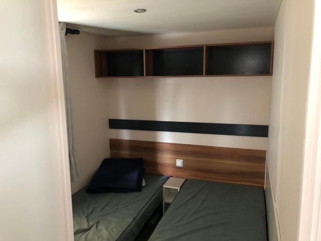 カルナックにあるCharmant Mobil home 6 placesのベッド2台と壁が備わる小さな客室です。