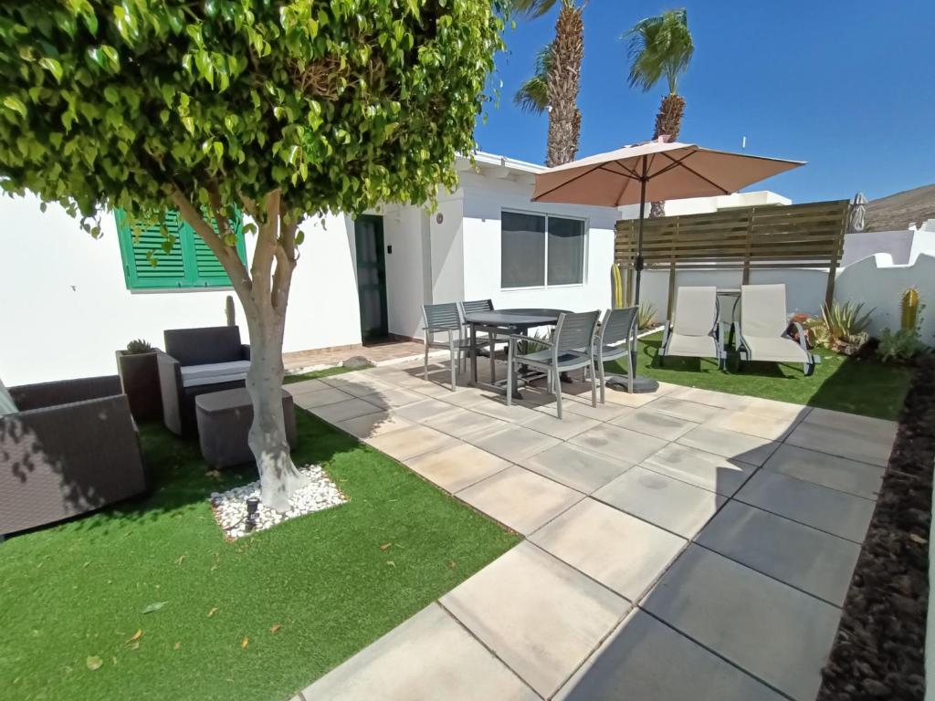 un patio con mesa y sombrilla en THE WHITE HOUSE with Pool - Playa Blanca, en Playa Blanca