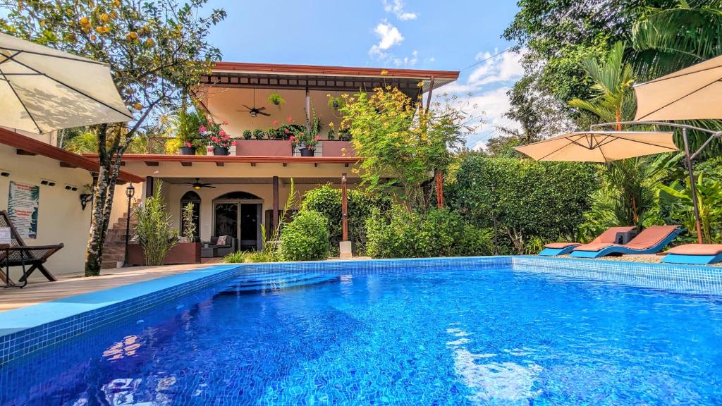 a swimming pool in front of a house with umbrellas at Jardín de los Monos in Matapalo