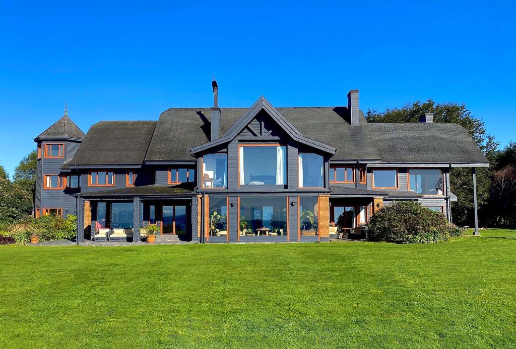 a large house with large windows and a green lawn at Casa Molino Hotel Boutique & Restaurant Puerto Varas in Puerto Varas