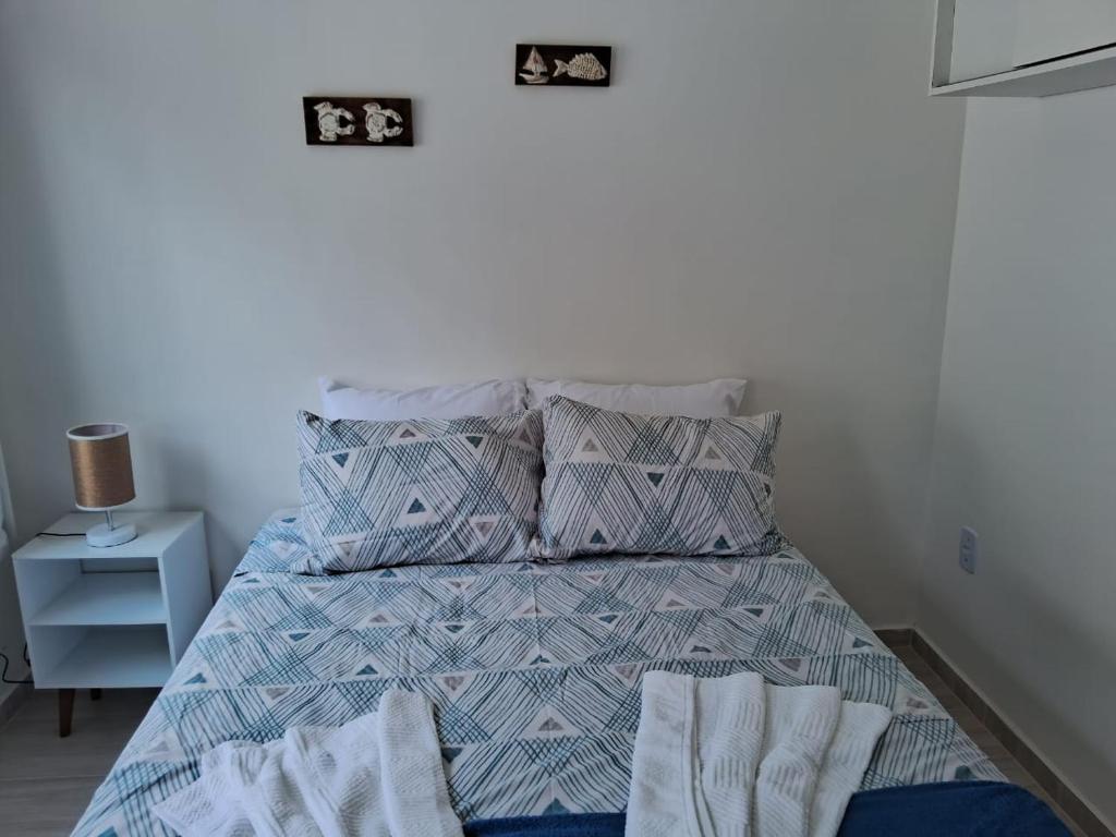 um quarto com uma cama com um edredão e almofadas azuis em Recanto Ganesha seu paraíso na praia, no Recanto de Itaipuaçu ao lado de Itacoatiara em Itacoatiara