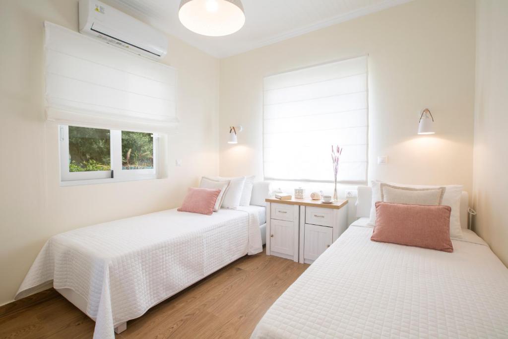 two beds in a bedroom with white walls at Villa Kallisti - private villa with hot tub, large garden, close to the beach in Ayía Varvára