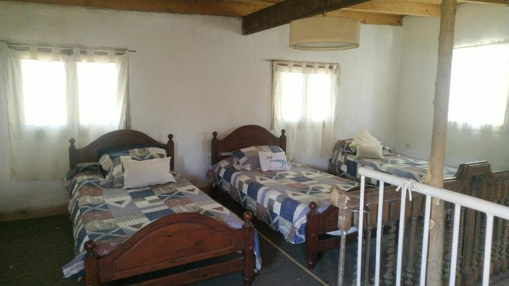a bedroom with two beds and two windows at Casa De Campo El Corral in Carmen de Areco