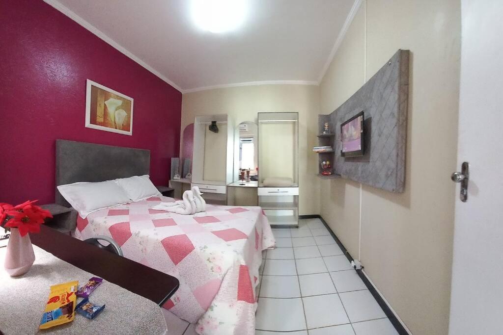 a bedroom with a bed with a red wall at Apartamento Mobiliado temporada in Aracaju
