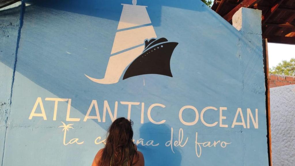 una mujer parada frente a un cartel con un velero en él en Cabaña El Faro, en Tubará