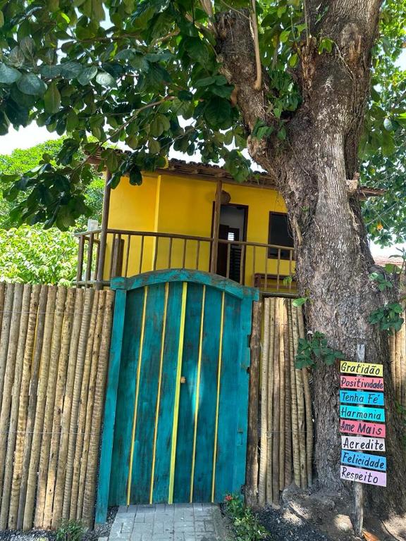 una casa detrás de una valla con una puerta y un árbol en Chalé Casa Vitoria - Quarto Inferior en Trancoso
