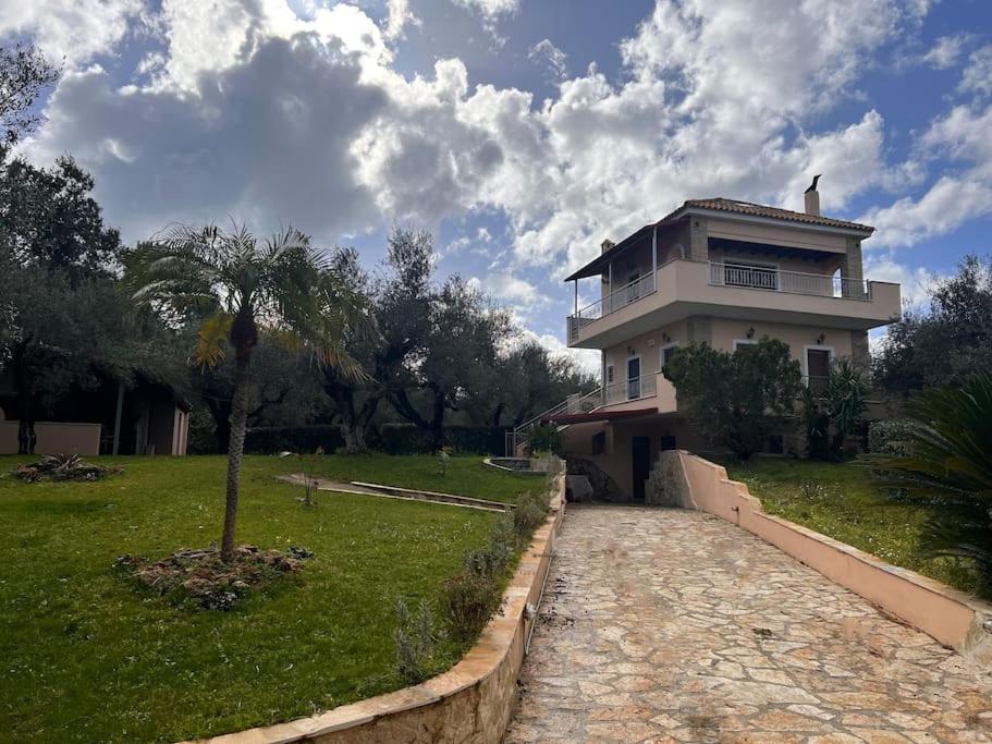 a house with a palm tree in front of a yard at VS Villa Killini in Káto Panayía