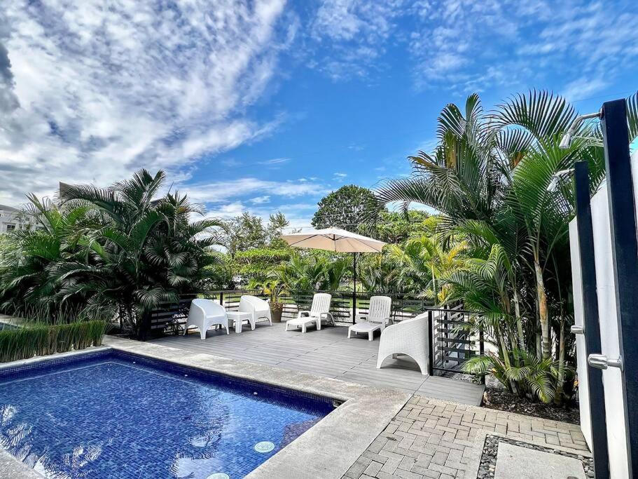 a patio with a pool and chairs and an umbrella at Modern & convenient condo in Jaco downtown in Jacó
