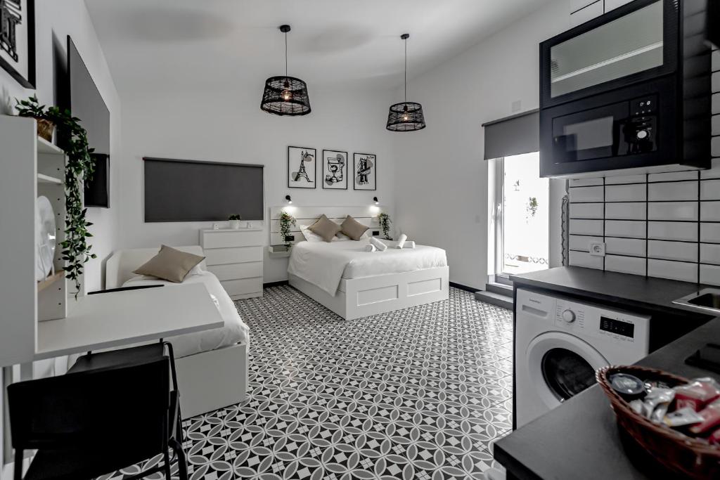 ein weißes Wohnzimmer mit einem Bett und einem TV in der Unterkunft Apartamentos Pino in Benidorm