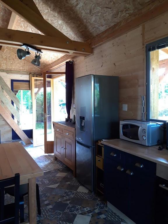 une cuisine avec un réfrigérateur en acier inoxydable et une table dans l'établissement CHALETS POUR FAMILLE ET AMIS, à La Chapelle-aux-Chasses