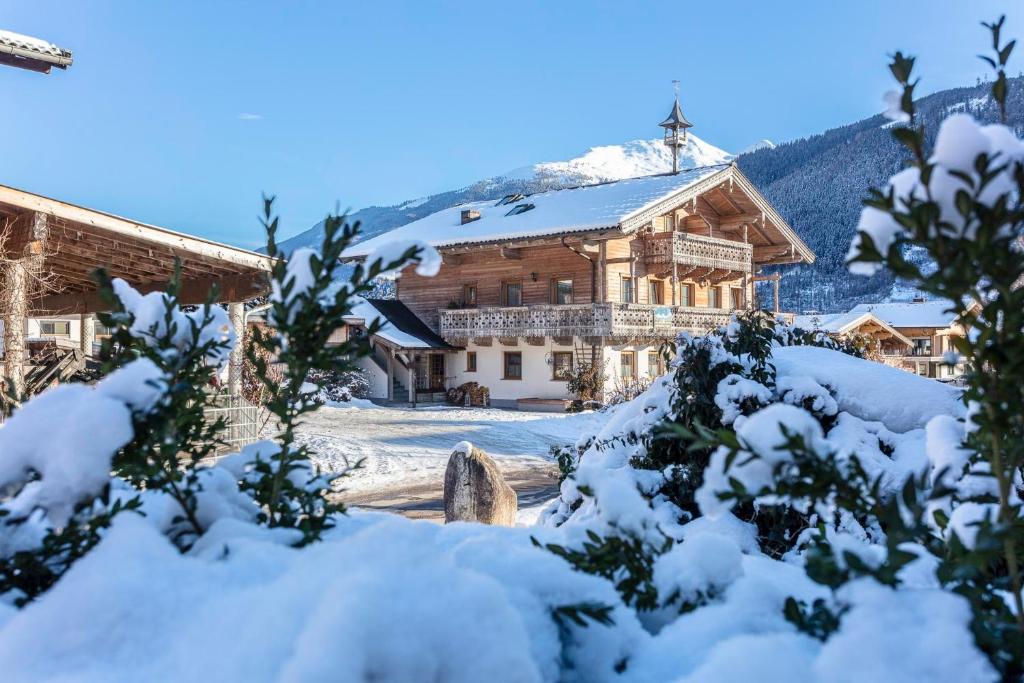 uma casa coberta de neve com uma cruz numa montanha em Ferienwohnungen am Biobauernhof Lahner em Bramberg am Wildkogel