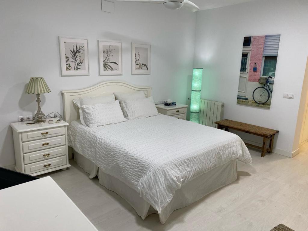 Montequinto的住宿－Habitación independiente, luminosa y perfecta para dos o una persona.，白色的卧室配有一张床和一张桌子,墙上有一辆自行车