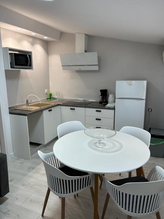 a white kitchen with a white table and chairs at Apartments Oliva in Poreč