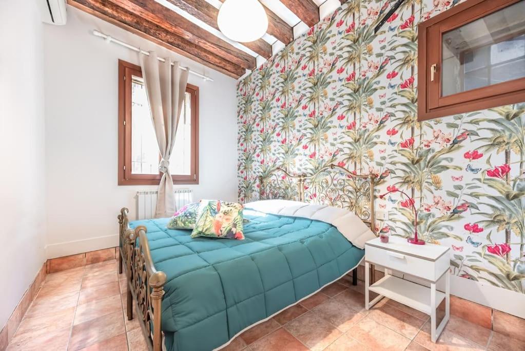 a bedroom with a blue bed and floral wallpaper at Guggenheim House [ Dorsoduro ] in Venice
