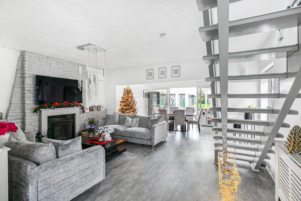 a living room with a fireplace and a christmas tree at Hampton Oasis with Heated Pool & Large Garden in Molesey