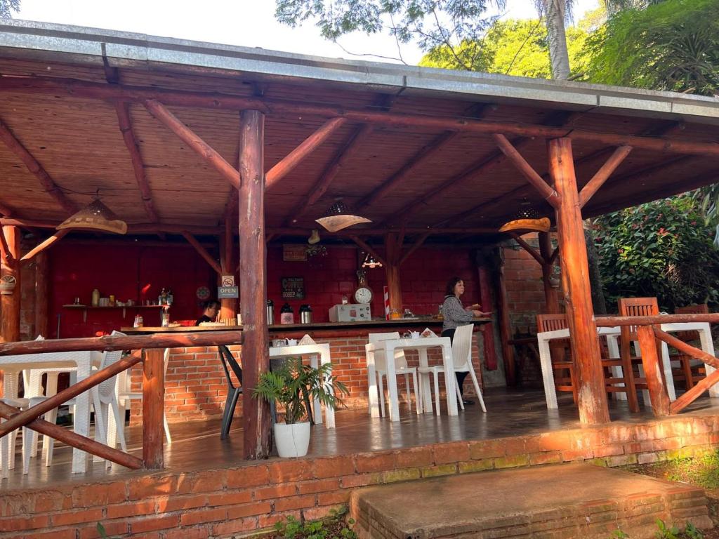 a wooden pavilion with a table and chairs and a person at Mainumby- Colibri Posada in Puerto Iguazú