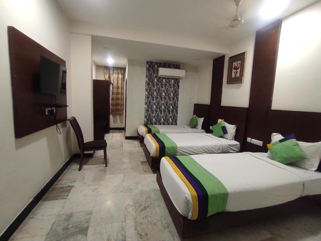 a hotel room with two beds and a television at Hotel Luxury Holiday - Banjara hills prime location in Hyderabad