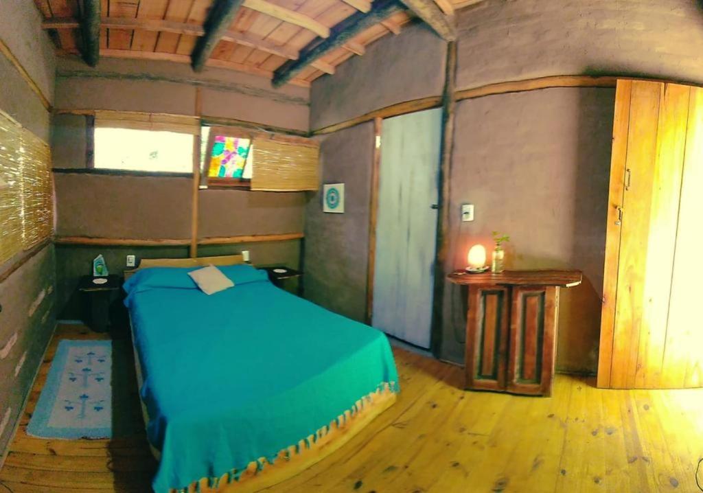 a room with a blue bed and a table at Eco Posada Tierra Fértil in Santa Ana
